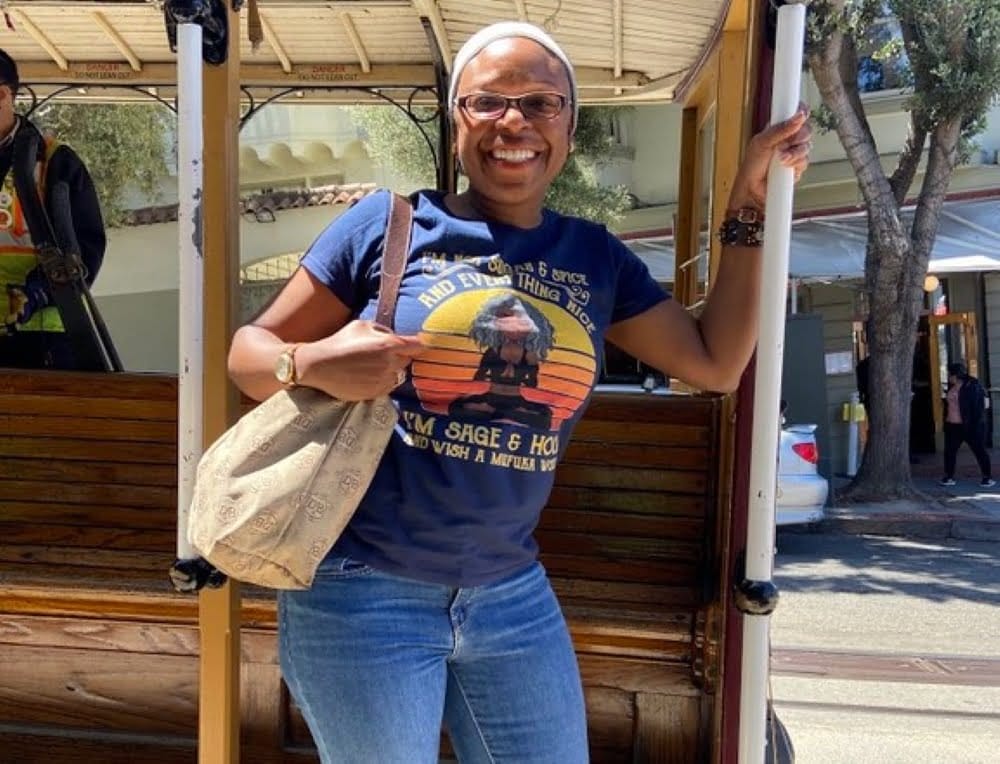 A woman in a t-shirt standing next to a cable car, capturing an uncollectible revenue moment.