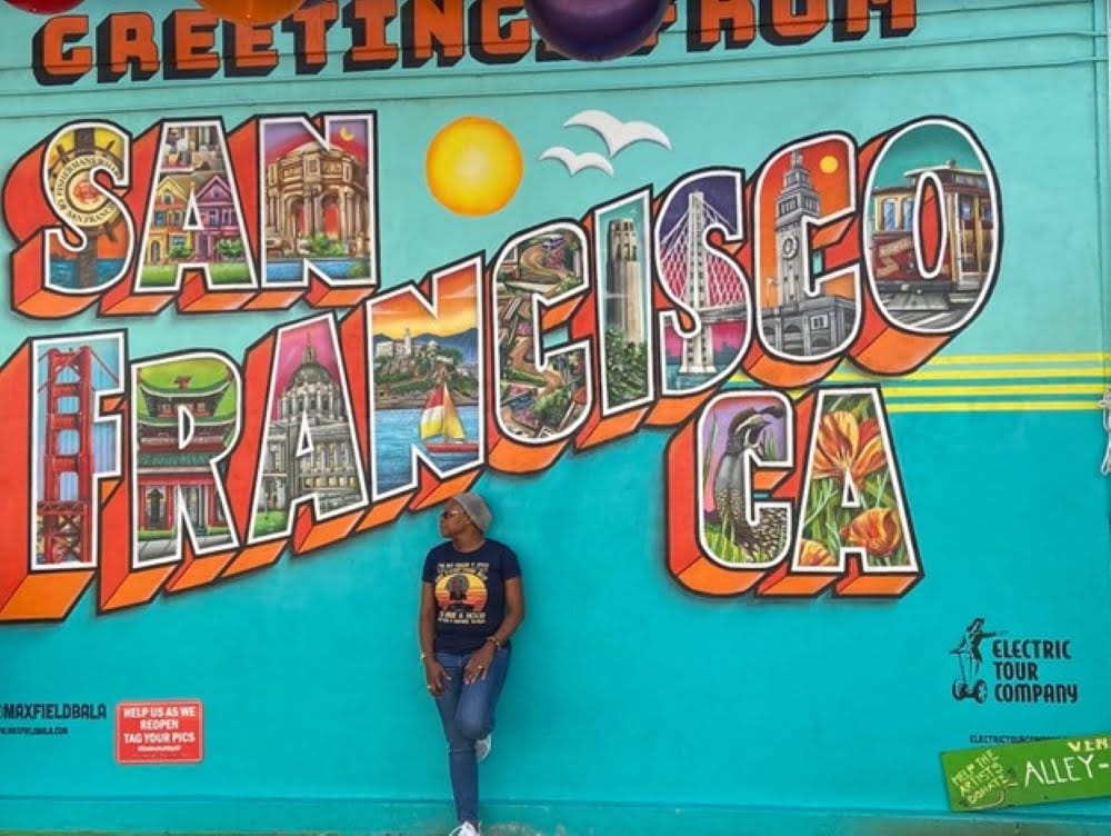 A woman standing in front of a vibrant mural in San Francisco.