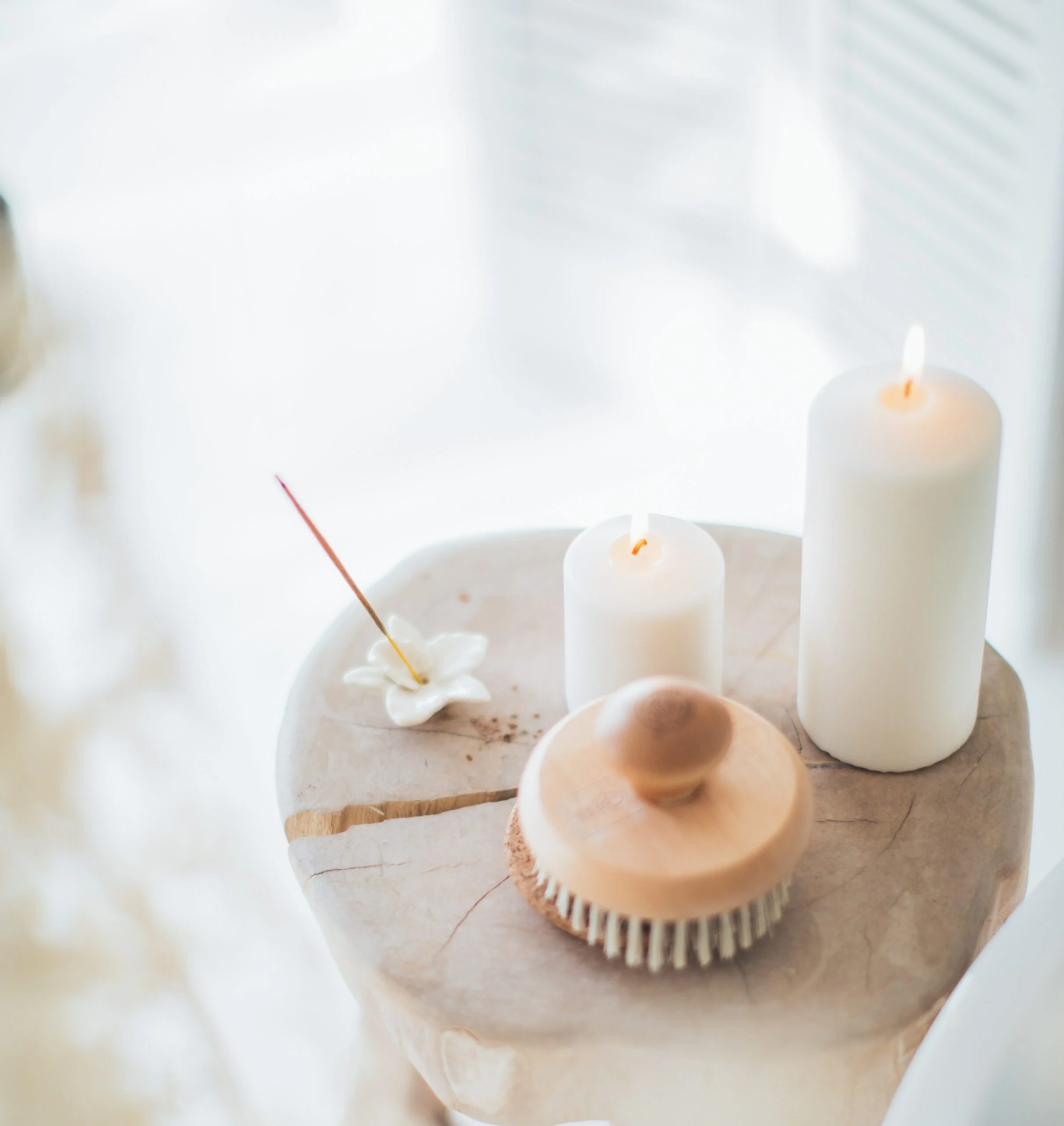 A wooden table with candles and a brush on it.
