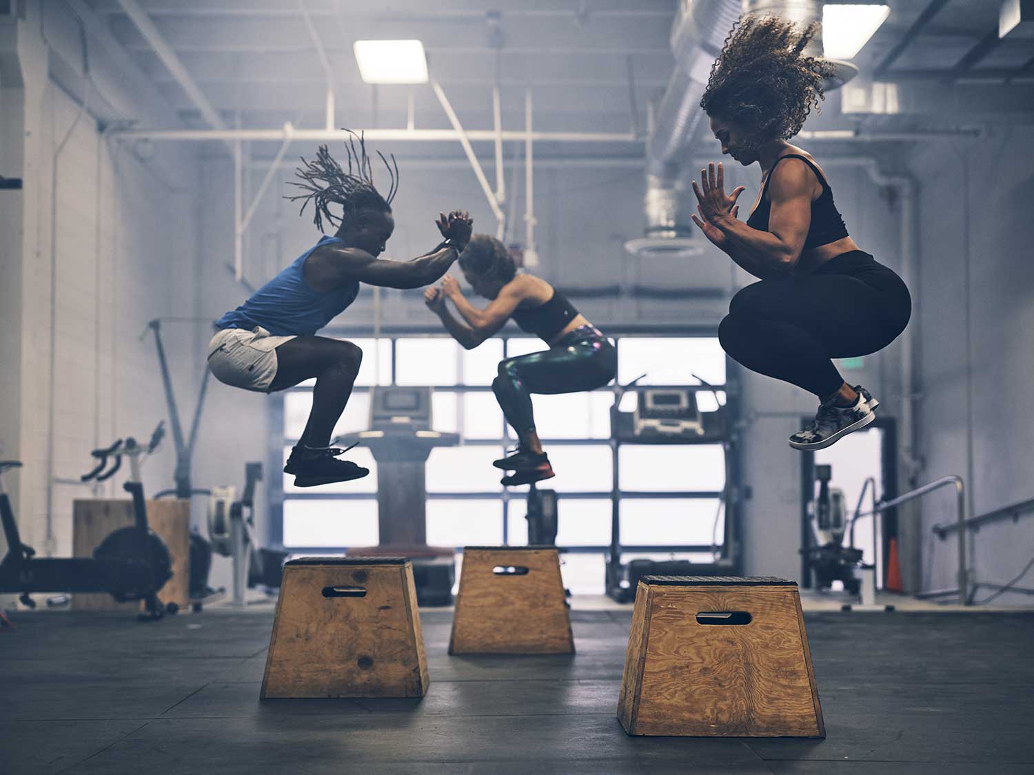 Three women doing jump squats in a gym.
